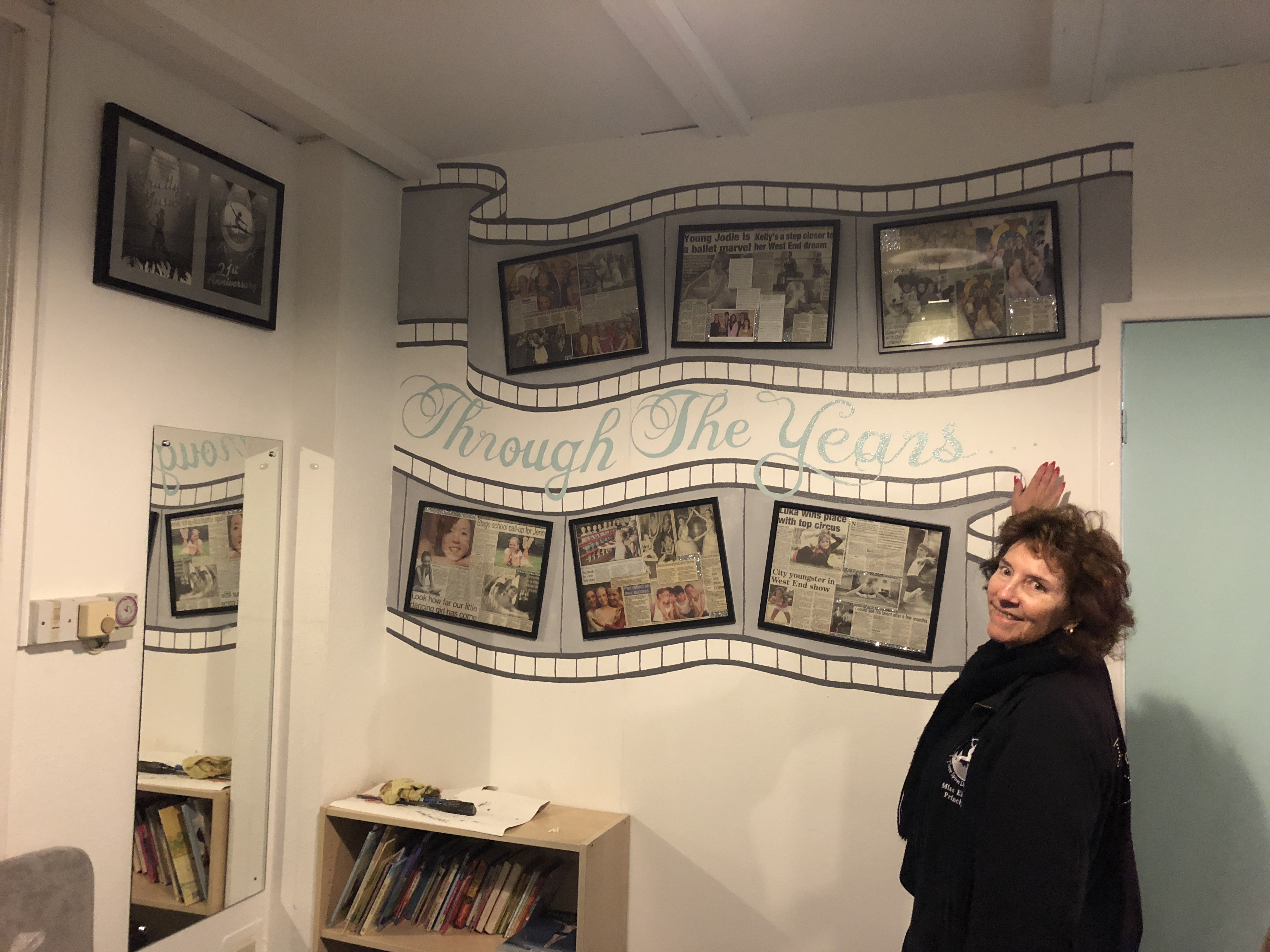 Elaine Ferry standing by newspaper clippings of stories about Three Spires Dance School Coventry 